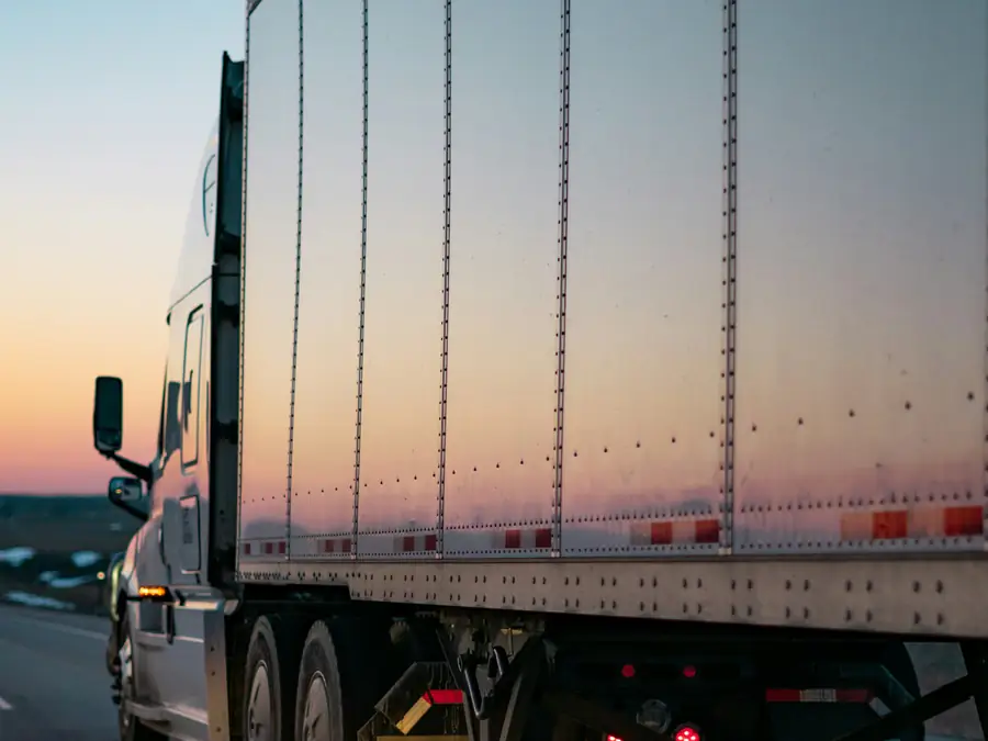 The side of a dry van trailer on the highway at sunset